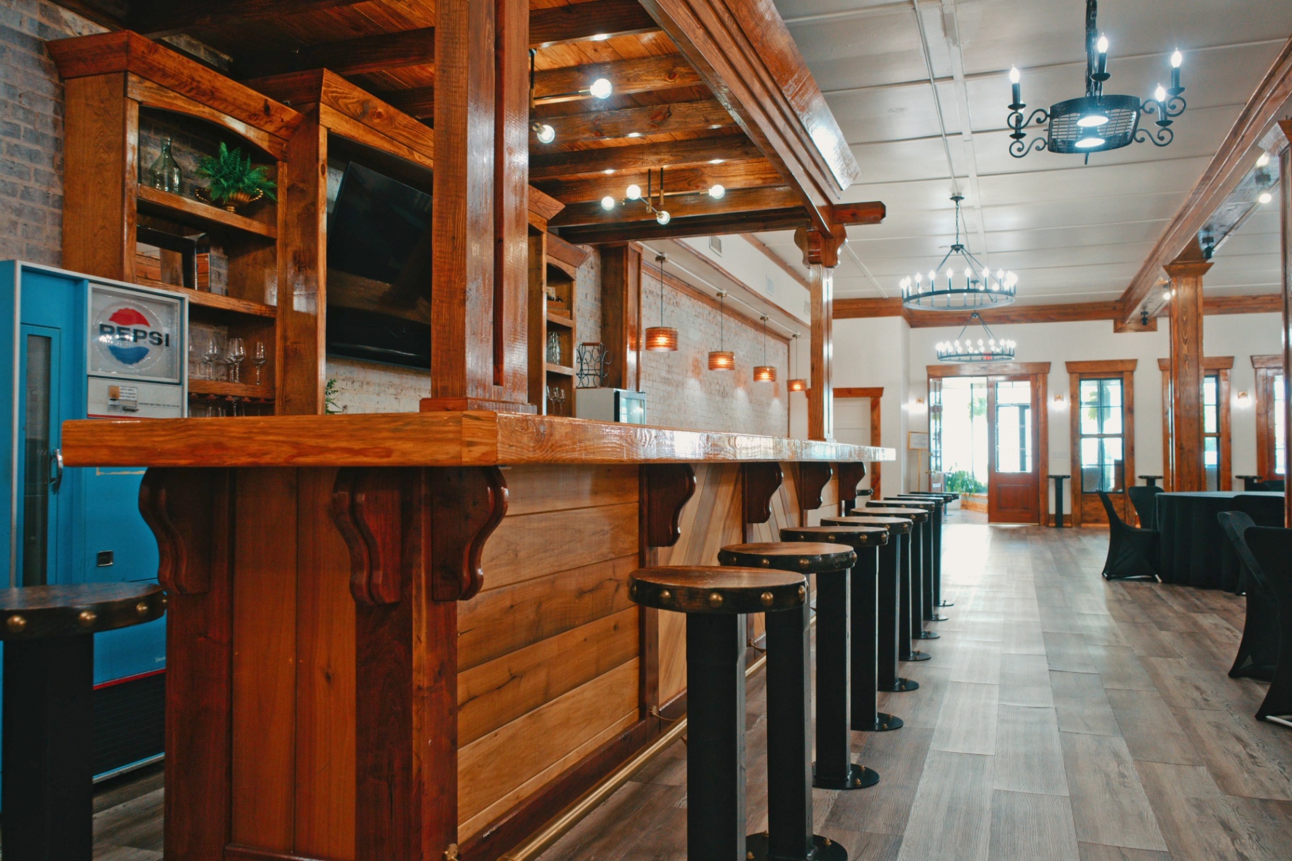 The in-house bar with reclaimed timber, leather-topped stools, and warm overhead chandeliers